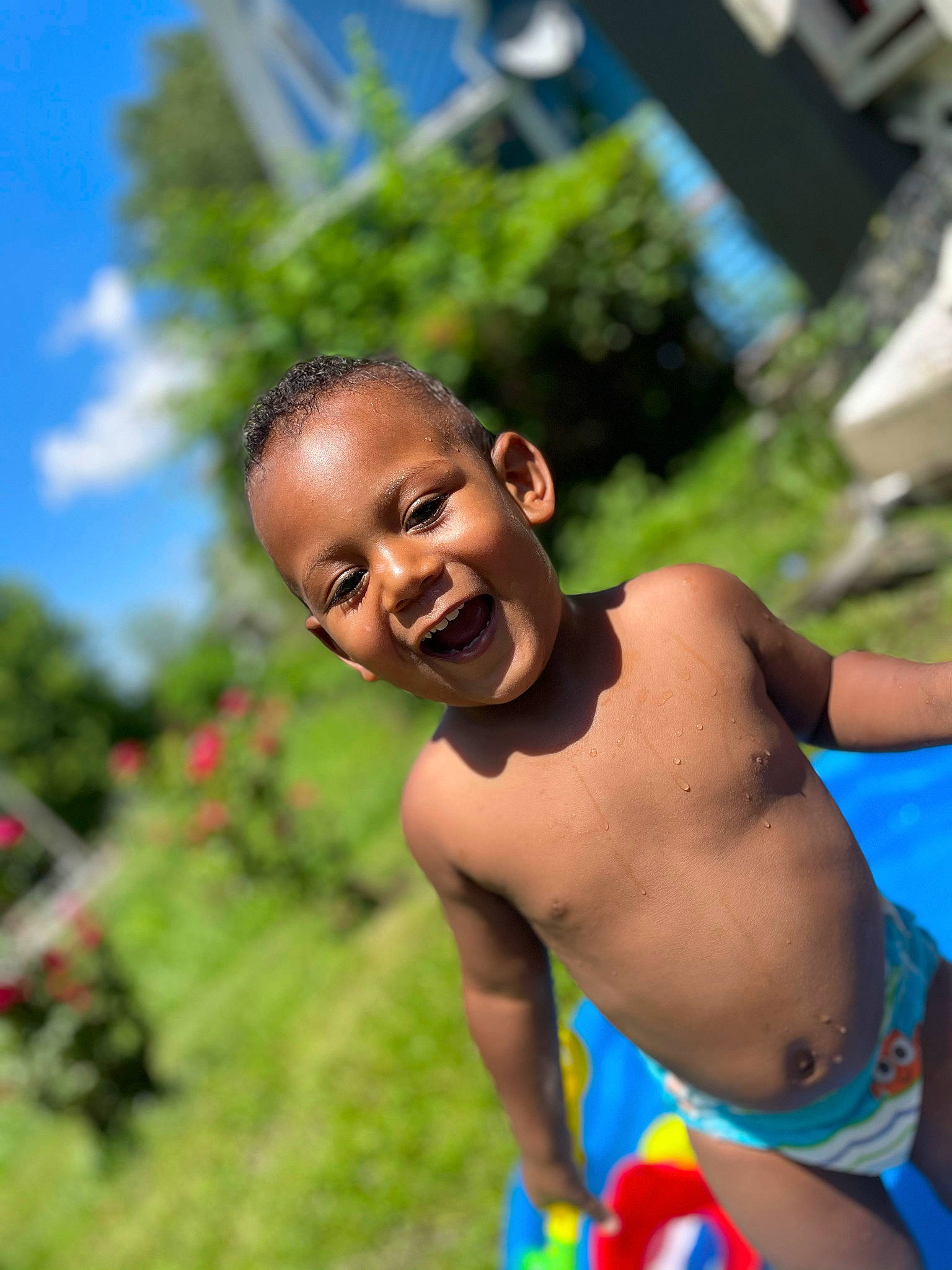 Kamari is registered to the contest to win money with this photo: barechested, blue, chest, child, event, fun, grass, happy, human_body, joy, leisure, people_in_nature, person, plant, recreation, sky, smile, swimwear, toddler, tree