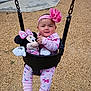 baby, child, swing, playground, plush_toy, minnie_mouse, pink_clothing, headband, flower, outdoor, wood_chips, happy, smile, toddler, chain, seat, person, toy, cute, fun