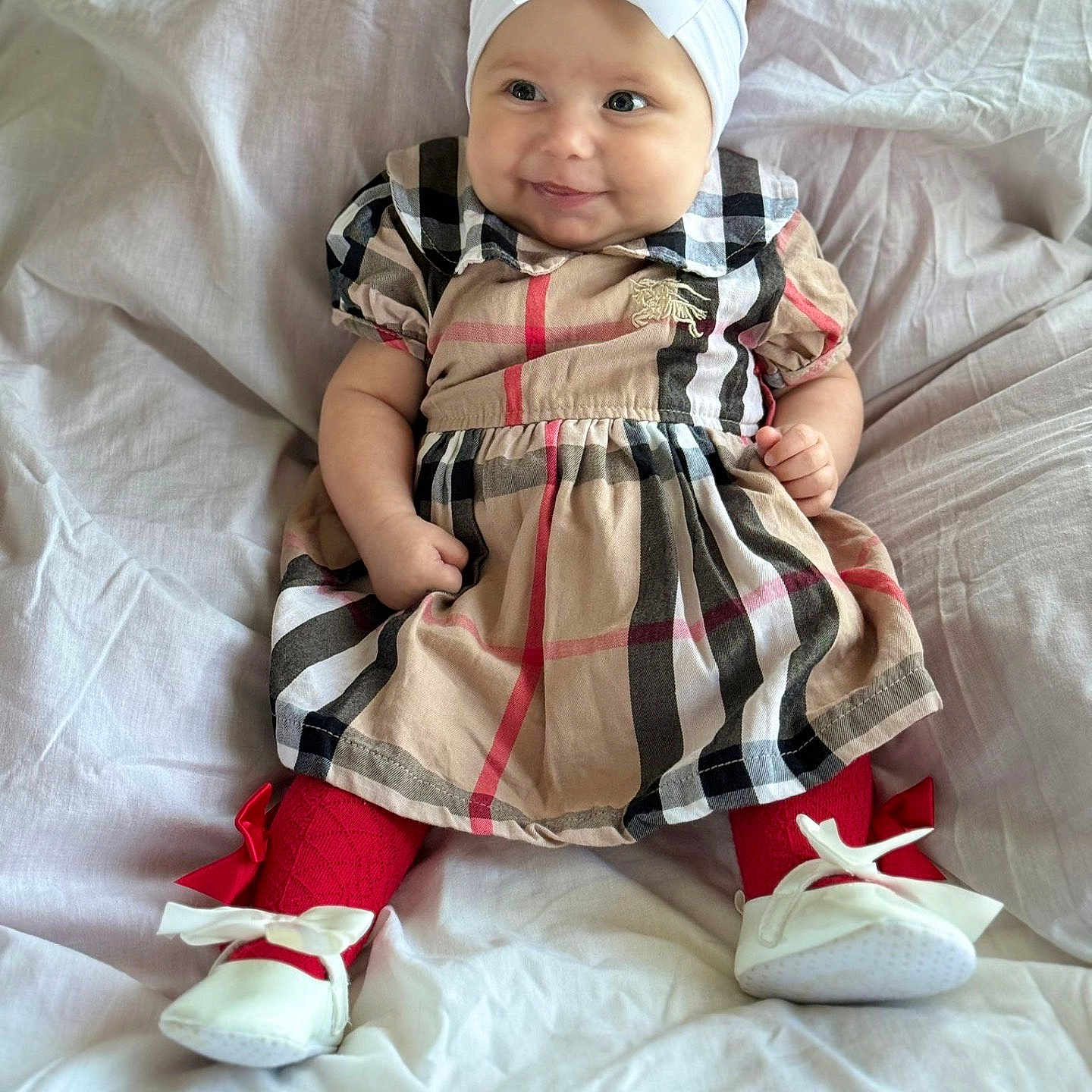 Delilah-Louise is registered to the contest to win money with this photo: baby, bow, child, cozy, cute, dress, fabric, happy, headband, indoors, infant, light, person, plaid, playful, portrait, red_tights, sitting, smiling, white_shoes