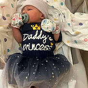 Nevaeh is registered to the contest to win money with this photo: newborn, baby, pacifier, mittens, tutu, dress, hat, blanket, hospital, wristband, infant, sleeping, cute, polka_dot, star_pattern, face, foot, lying_down, person, child