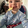 Myles is registered to the contest to win money with this photo: baby, child, high_chair, cracker, blue_onesie, smiling, face, mouth, cheeks, indoor, happy, infant, seat, cute, portrait, person, clothing, food, snack, baby_food
