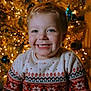 child, smiling, sweater, holiday, christmas_tree, lights, festive, cozy, indoors, portrait, happy, young, red, white, patterned, warm, celebration, decoration, winter, cute