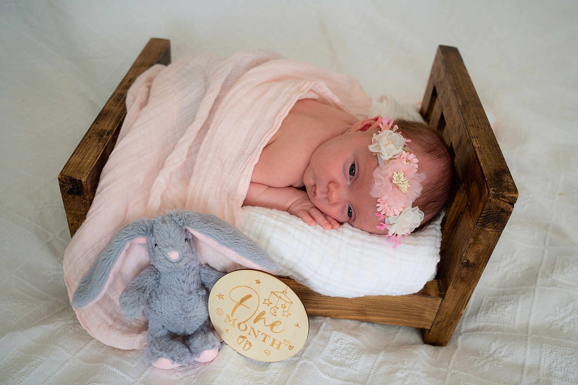 Mia-Bella is registered to the contest to win money with this photo: baby, newborn, blanket, wooden_bed, flower_headband, plush_toy, bunny, milestone_sign, one_month, sleeping, cute, infant, soft_toys, pink, white, wood, portrait, resting, indoor, baby_bed