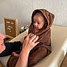 Louis a rejoint le concours — aidez-le/la à gagner de superbes lots ! baby, infant, towel, hooded_towel, person, adult_hand, changing_table, wooden_sign, indoor, curious, wrapped, skin, face, expression, newborn, cozy, soft, celebration, table, furniture