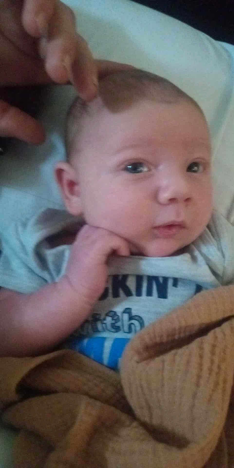 Ezra is registered to the contest to win money with this photo: baby, infant, hand, face, eyes, blanket, clothing, person, skin, head, newborn, cute, portrait, expression, human, child, cozy, toddler, soft, indoor