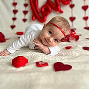 Arya is registered to the contest to win money with this photo: baby, infant, headband, red_bow, heart_decorations, love_balloon, white_blanket, lying_down, cute, portrait, holiday_theme, valentines_day, decorations, close_up, indoor, child, adorable, smiling, soft_texture, celebration