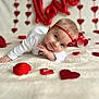 baby, infant, headband, red_bow, heart_decorations, love_balloon, white_blanket, lying_down, cute, portrait, holiday_theme, valentines_day, decorations, close_up, indoor, child, adorable, smiling, soft_texture, celebration