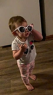 Kylee is registered to the contest to win money with this photo: baby, baby_toddler_clothing, child, ear, eyewear, flooring, fun, glasses, goggles, happy, hardwood, pattern, person, personal_protective_equipment, sleeve, sunglasses, t_shirt, thumb, toddler, vision_care