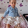 toddler, child, denim_jacket, floral_skirt, sandals, pink_blanket, butterfly_wall_decals, indoor, furniture, bed, cute, portrait, serious_expression, girl, hair_tie, earrings, skin, feet, clothing, room_decor