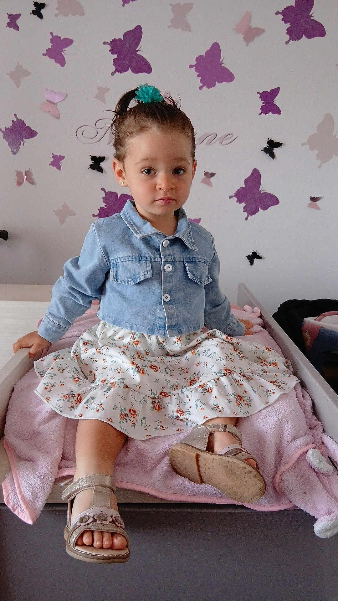 Maélane a rejoint le concours — aidez-le/la à gagner de superbes lots ! toddler, child, denim_jacket, floral_skirt, sandals, pink_blanket, butterfly_wall_decals, indoor, furniture, bed, cute, portrait, serious_expression, girl, hair_tie, earrings, skin, feet, clothing, room_decor