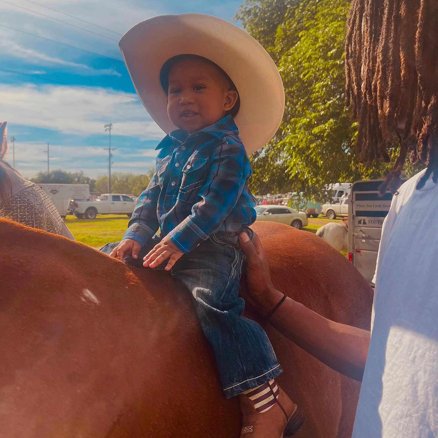 Charvis Jr joined the competition — help win amazing prizes! animal, blue_sky, boots, child, cowboy_hat, daytime, grass, hand, horse, jeans, outdoor, person, plaid_shirt, ranch, smile, sunlight, support, toddler, tree, vehicle