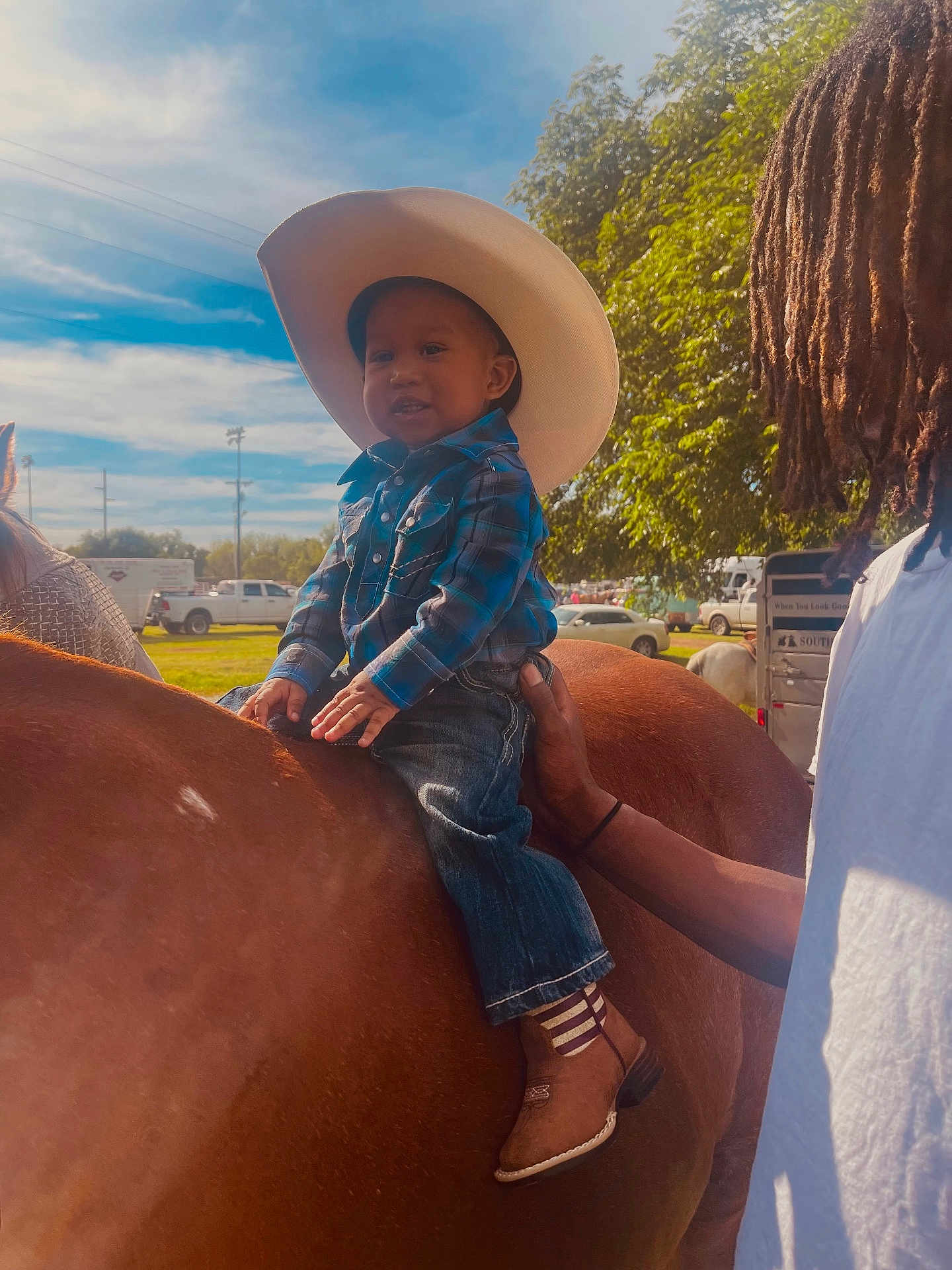 Charvis Jr joined the competition — help win amazing prizes! toddler, child, horse, cowboy_hat, boots, blue_sky, outdoor, person, plaid_shirt, jeans, animal, sunlight, hand, tree, grass, vehicle, daytime, ranch, support, smile