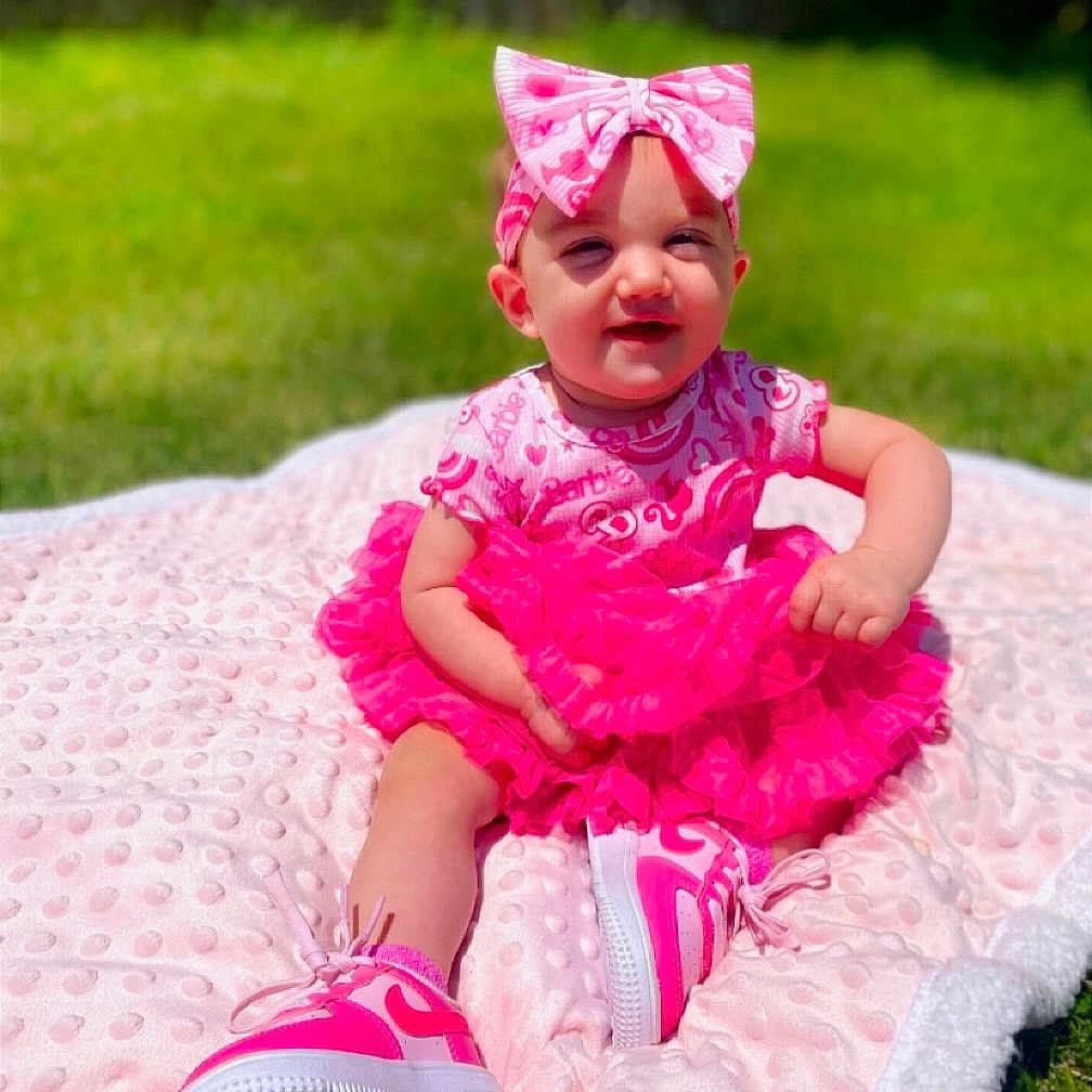 Kaiya is registered to the contest to win money with this photo: baby, child, pink, dress, headband, bow, sneakers, blanket, outdoor, grass, smiling, cute, tutu, sunny, happy, sitting, young_child, fashion, footwear, portrait