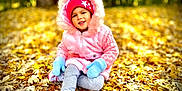 Roseary is registered to the contest to win money with this photo: autumn, beanie, casual_wear, child, daylight, fall, footwear, forest, happy, leaves, mittens, nature, outdoor, pink_jacket, portrait, seasonal, sitting, smiling, toddler, young