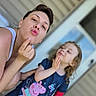 adult, child, woman, kiss, pose, smile, peppa_pig, tshirt, red_cast, hand_on_chin, outdoor, door, house, curly_hair, fun, playful, family, portrait, casual, daylight