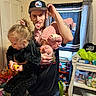 Lilyana is registered to the contest to win money with this photo: man, child, toddler, indoor, playful, family, cap, curtains, toys, clothing, upside_down, black_shirt, pink_outfit, window, shelf, storage, carpet, smile, room, holding