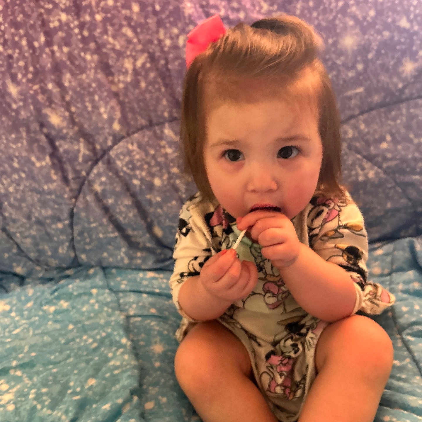 Lilyana is registered to the contest to win money with this photo: toddler, child, baby, lollipop, bow, pink_bow, sitting, blanket, starry_pattern, curious, indoors, clothing, cute, young_child, face, hand, legs, expression, soft_lighting, portrait