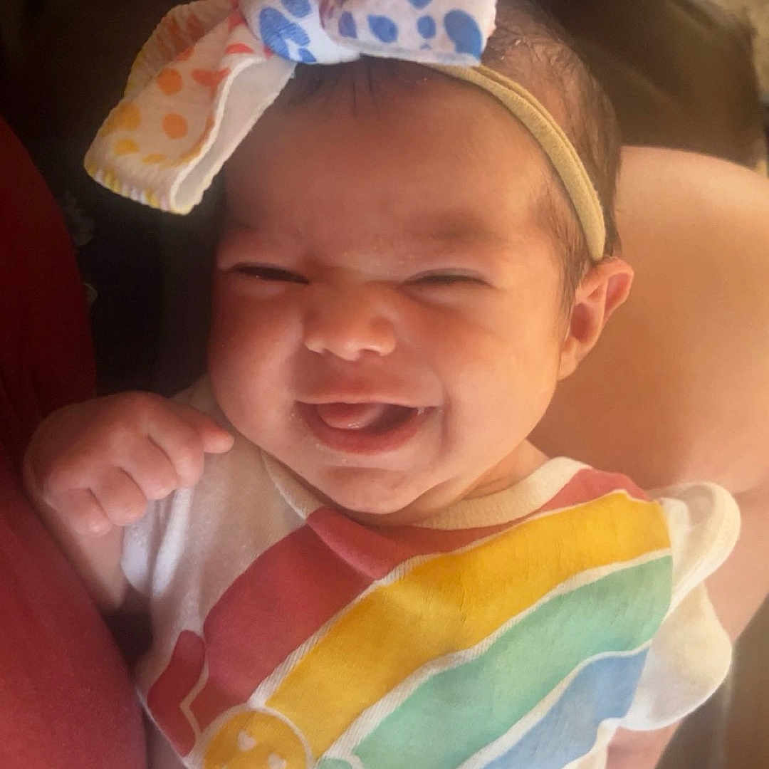 Alora joined the competition — help win amazing prizes! baby, infant, smile, tongue_out, headband, bow, polka_dot, rainbow, love, clothing, cute, happy, person, portrait, hand, skin, sitting, indoor, cozy, candid