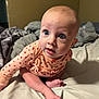 baby, infant, blue_eyes, sitting, bed, blanket, clothing, long_sleeve, peach, ladybug_pattern, curious, indoors, skin, foot, hand, head, expression, portrait, child, cute