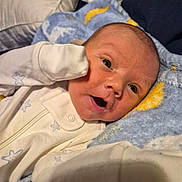Axell is registered to the contest to win money with this photo: baby, newborn, infant, face, eyes, mouth, onesie, clothing, blanket, blue_blanket, yellow_pattern, white_clothing, cute, lying_down, soft_texture, small_hand, expression, indoors, portrait, cozy