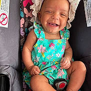 Malasiah is registered to the contest to win money with this photo: baby, smiling, hat, dress, car_seat, butterfly_pattern, child, infant, happy, cute, portrait, sitting, clothing, colorful, person, seatbelt, indoors, skin, young, headwear