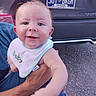 Wyatt is registered to the contest to win money with this photo: arm, baby, bib, car, child, clothing, drool, expression, eyes, face, gravel, hand, holding, license_plate, outdoor, parent, person, skin, smiling, vehicle