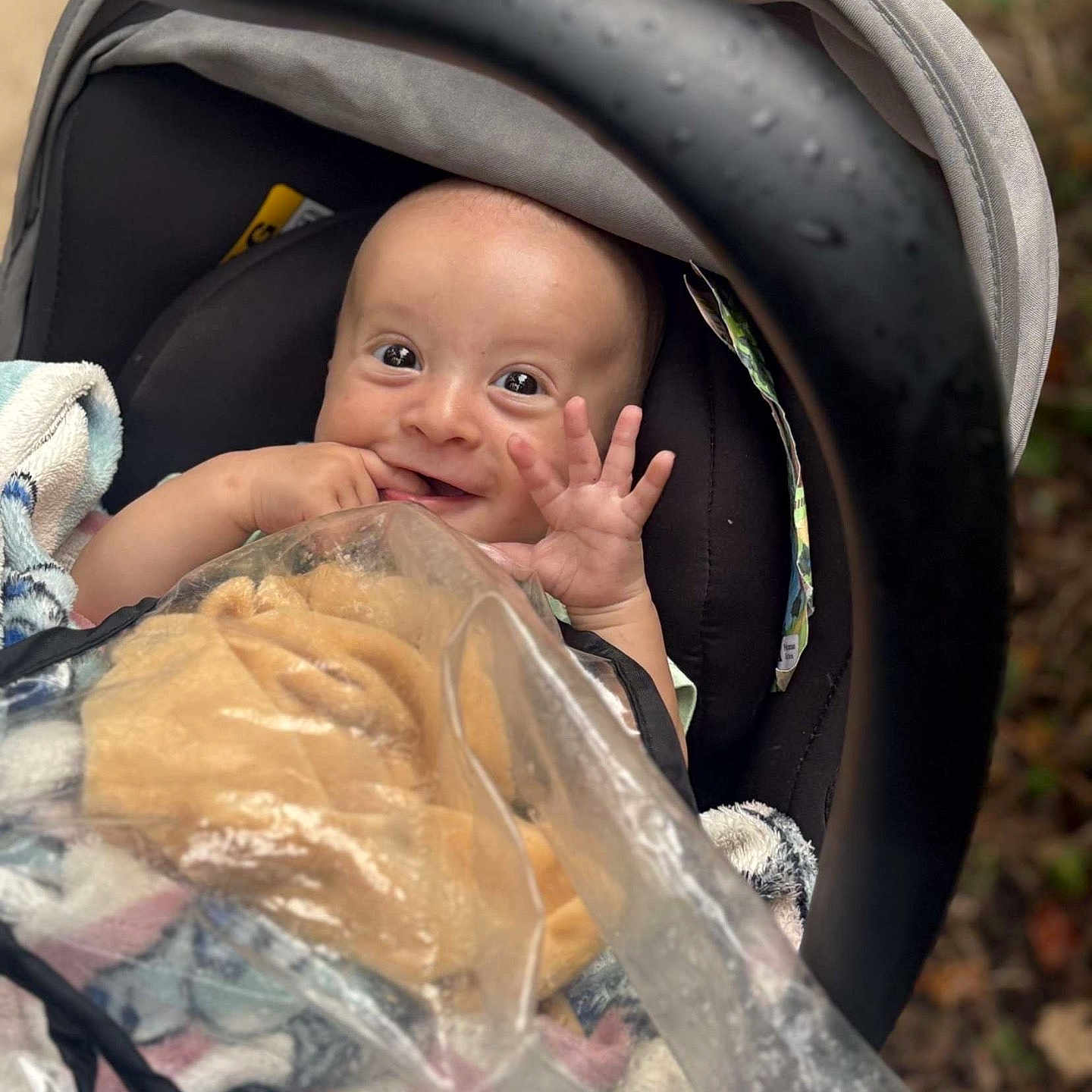 Mylow a rejoint le concours — aidez-le/la à gagner de superbes lots ! baby, baby_carrier, blanket, child, clothing, cozy, cute, face, hand, happy, head, infant, outdoor, person, plastic_cover, portrait, rain_drops, seat, smile, stroller