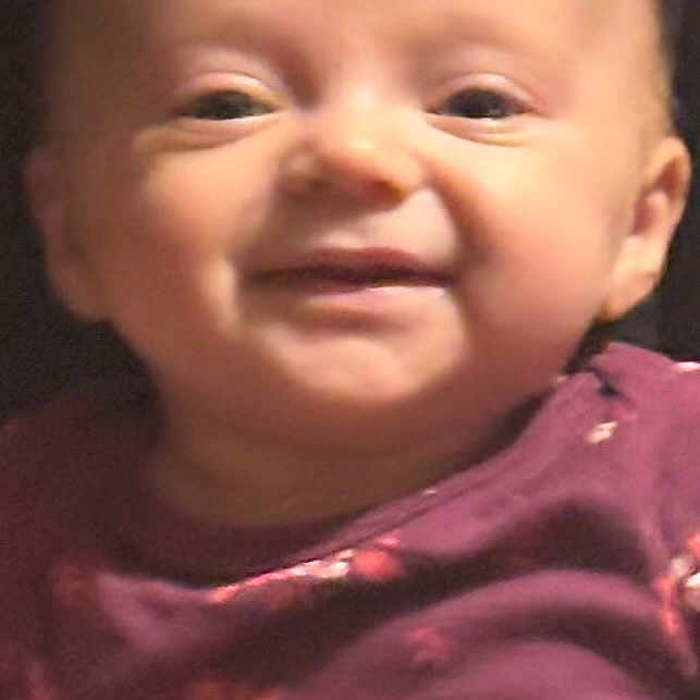 Willow is registered to the contest to win money with this photo: apparel, baby, cheerful, child, closeup, clothing, cute, expression, face, floral, happiness, head, indoors, infant, person, portrait, purple, skin, smiling, young