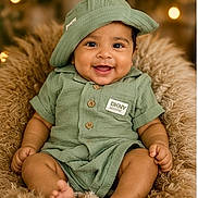 Viyaan is registered to the contest to win money with this photo: baby, bokeh, buttoned_shirt, child, cozy, cushion, cute, face, fluffy, green_clothing, happy, hat, headwear, indoors, infant, portrait, sitting, skin, smiling, warm_lighting