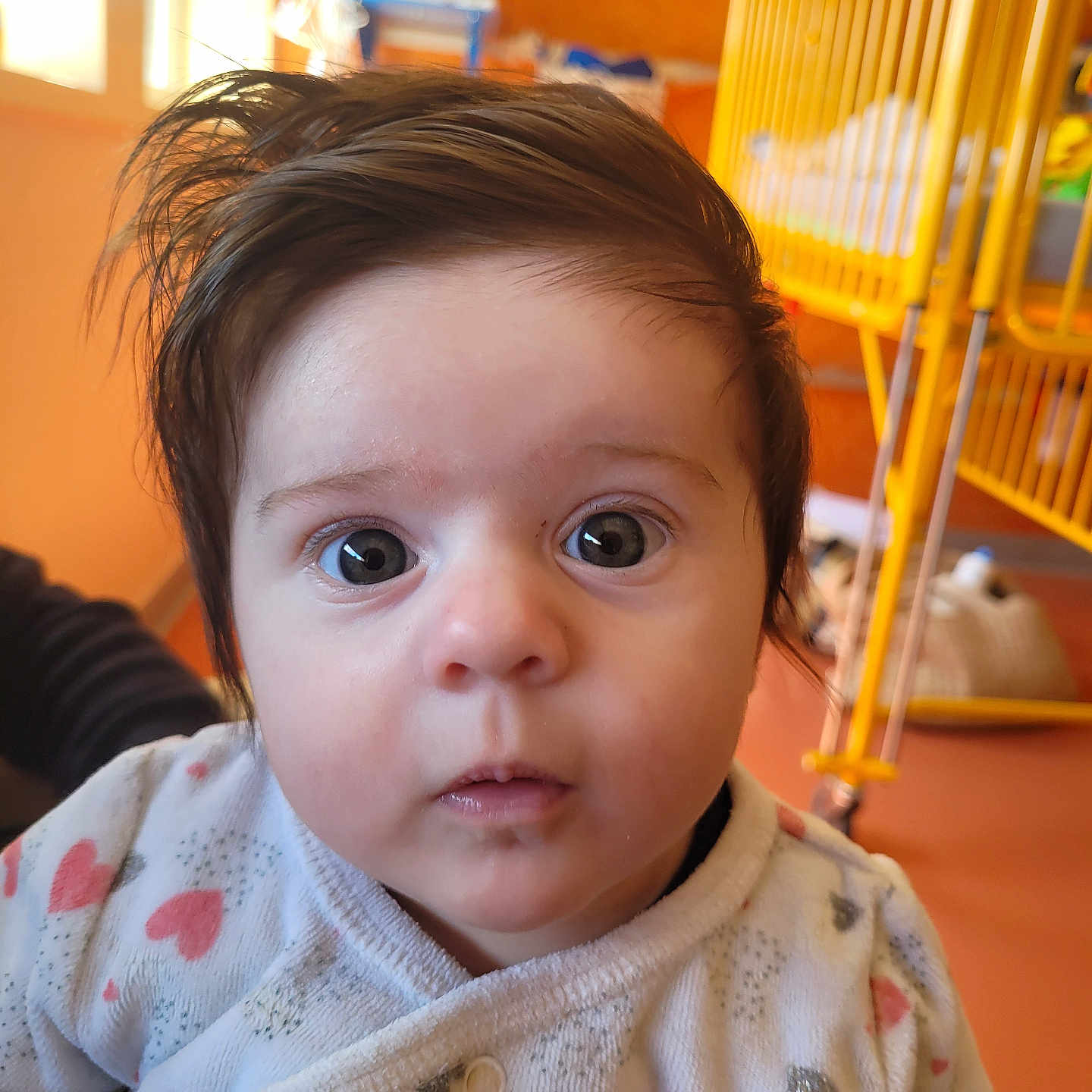 Octavia participe au concours pour gagner de l'argent avec cette photo : baby, child, face, eyes, hair, onesie, hearts, indoor, crib, yellow, curious, expression, portrait, infant, cute, person, clothing, soft, warm, cozy