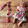 baby, infant, flower, headband, dress, floral_pattern, number_one, wooden_floor, flooring, celebration, birthday, cute, child, laying_down, pink, decor, fabric, person, young_child, portrait