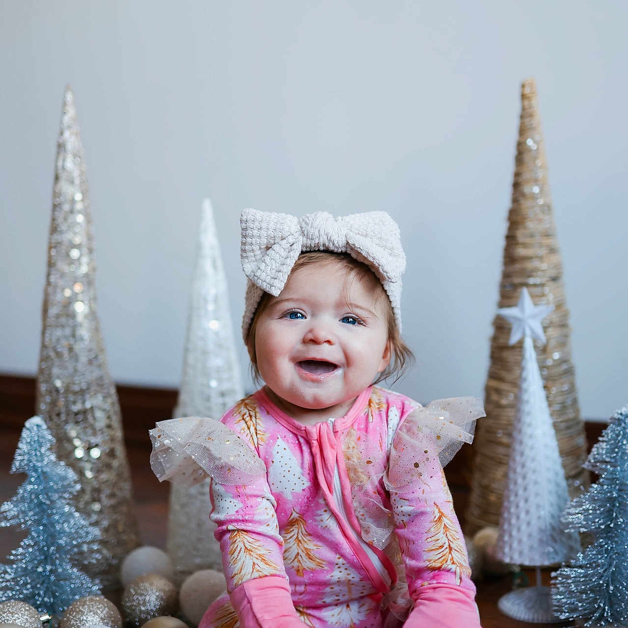 Auburn is registered to the contest to win money with this photo: baby, bow, celebration, child, christmas, cute, decorative_trees, festive, floor, happy, headband, holiday_decor, indoor, infant, ornaments, pink_clothing, portrait, sitting, smiling, winter