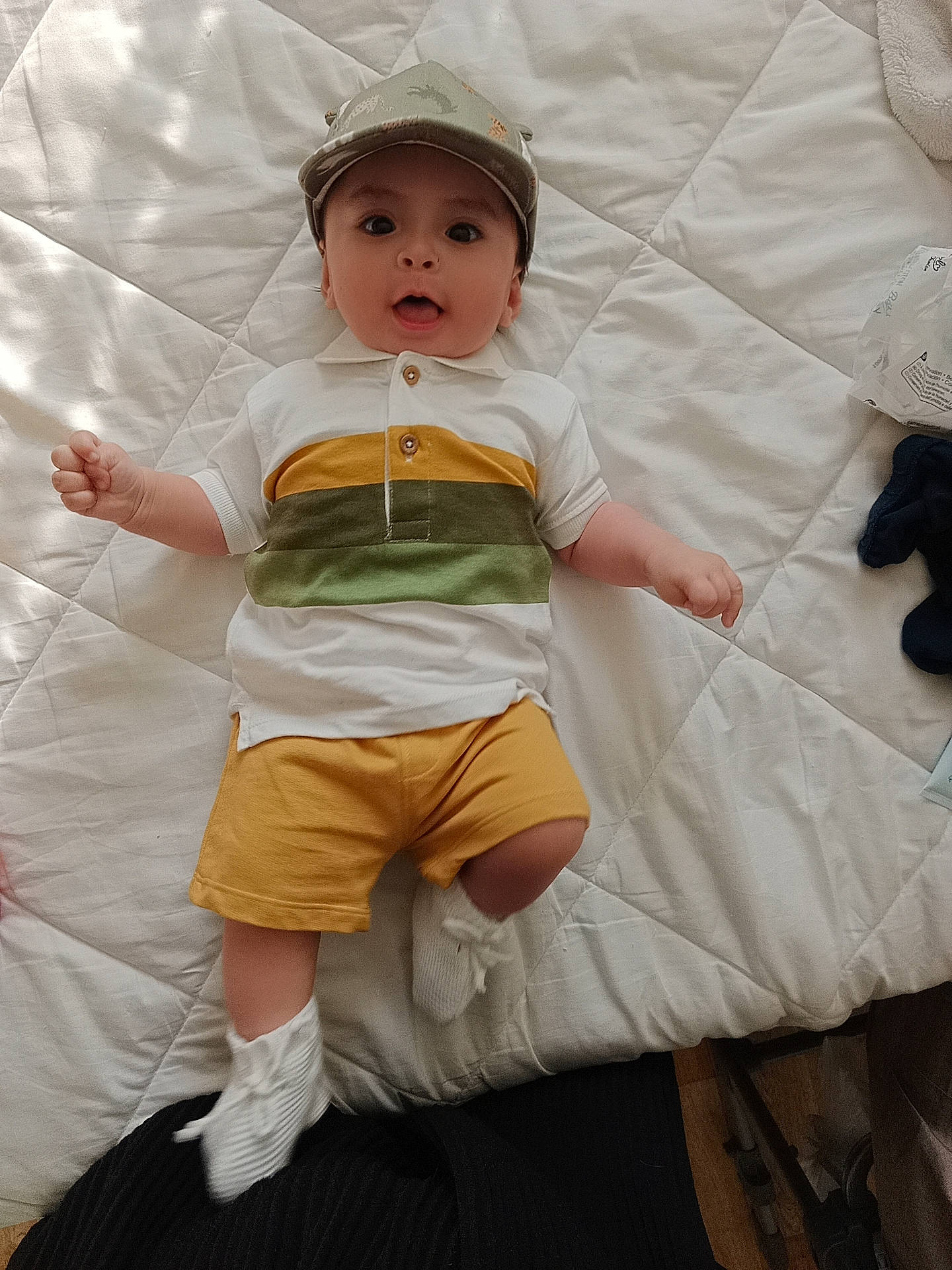 Aarón a rejoint le concours — aidez-le/la à gagner de superbes lots ! abdomen, baby, baby_products, baby_toddler_clothing, child, comfort, eye, face, fun, hat, headwear, human_leg, knee, linens, pattern, person, shorts, sitting, sleeve, surprise