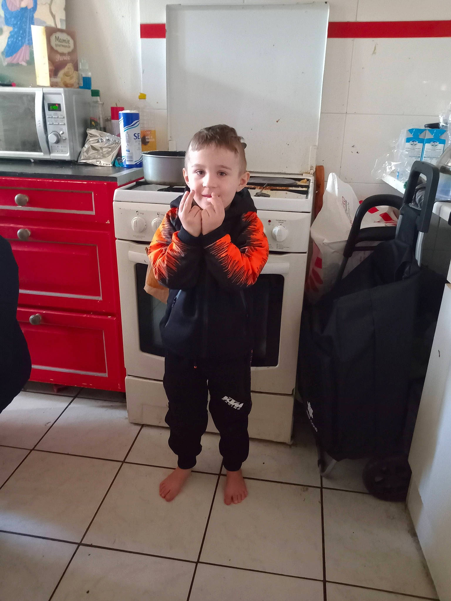 Angelo a rejoint le concours — aidez-le/la à gagner de superbes lots ! bag, cabinetry, chest_of_drawers, child, comfort, cupboard, drawer, dresser, floor, flooring, kitchen, kitchen_appliance, leg, luggage_and_bags, major_appliance, person, picture_frame, room, standing, television