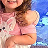 child, girl, smiling, curly_hair, dress, bunny_print, arm, hug, blue_background, aquarium, rocks, happy, portrait, indoor, cute, person, clothing, animal_print, baby, young