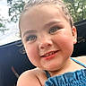 Kaylee is registered to the contest to win money with this photo: child, smiling, face, close_up, outdoor, greenery, blue_top, curly_hair, happy, young, portrait, natural_light, skin, eyes, person, cute, summer, daylight, expression, childhood
