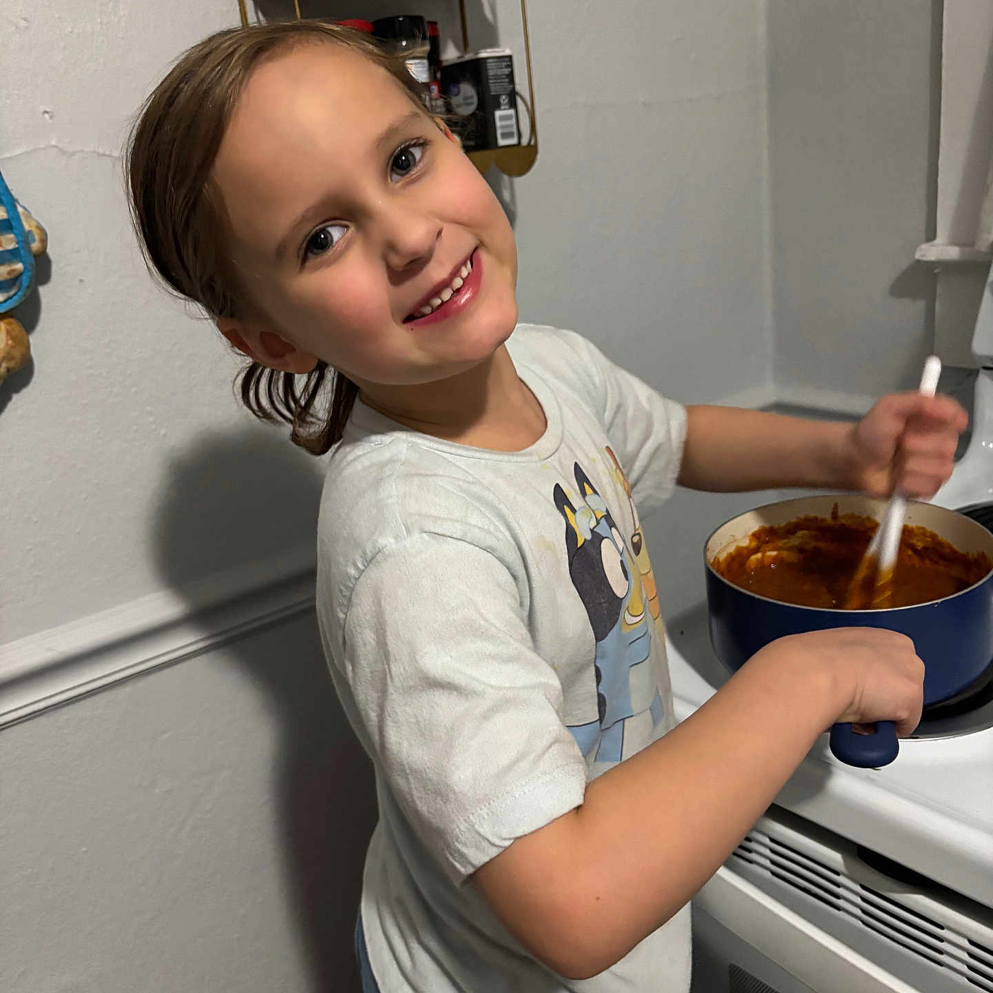 Miyah joined the competition — help win amazing prizes! appliance, cartoon, casual_clothing, child, cooking, food, happy, home, indoor, kitchen, light, person, pot, shelf, smiling, spices, spoon, stove, tshirt, young