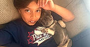 Smalls joined the competition — help win amazing prizes! child, puppy, dog, portrait, couch, indoors, sitting, lying_down, companion, pet, gray_dog, short-haired_dog, sleepy, relaxed, face, human, animal, shirt, furniture, home