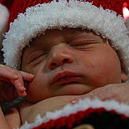 Rafael is registered to the contest to win money with this photo: baby, blanket, button, christmas, closeup, cozy, cute, face, hand, hat, holiday, infant, knitted, peaceful, portrait, red, santa_hat, skin, sleeping, white