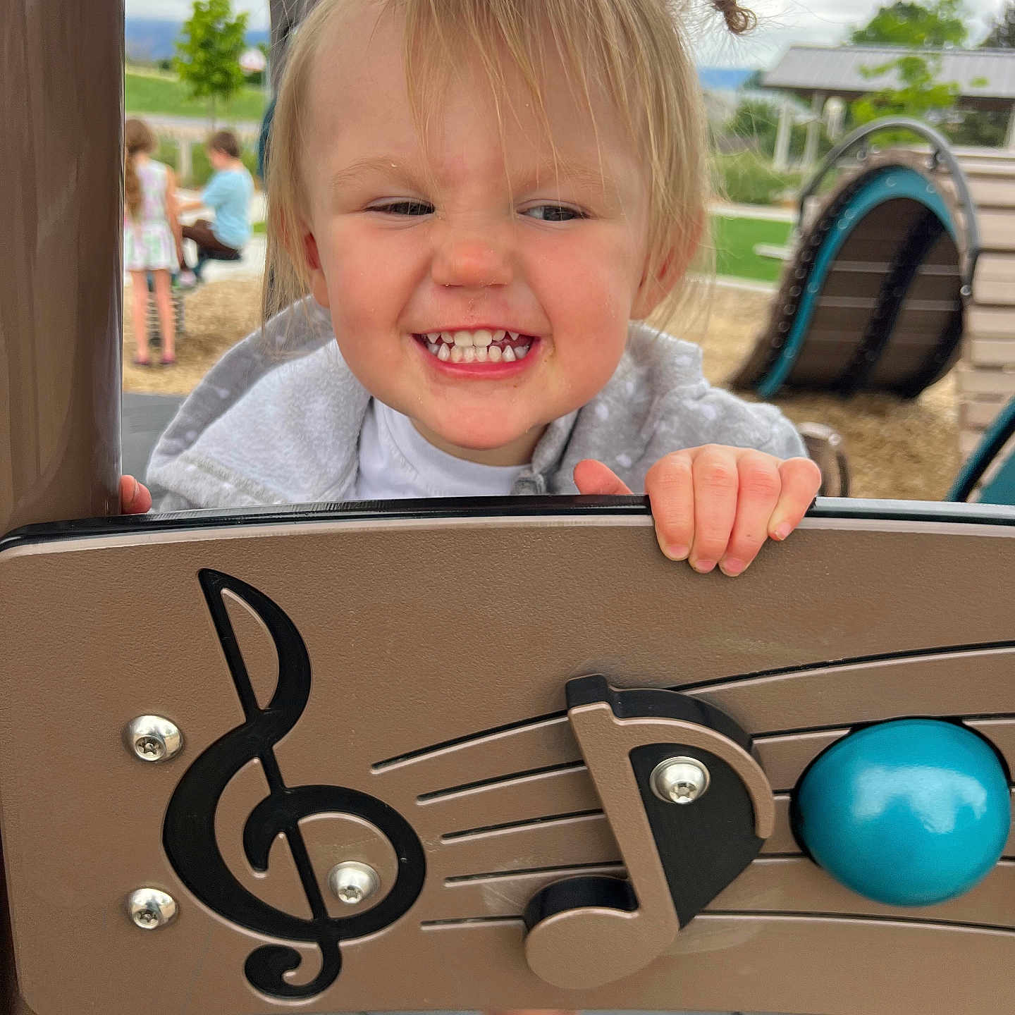 Lilith is registered to the contest to win money with this photo: child, clothing, daylight, expression, face, fun, hair, hand, happy, music, musical_notes, outdoor, park, person, play_equipment, playground, recreation, smiling, toddler, toy