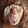 newborn, baby, swaddled, pink, headband, wooden_bowl, lace, dried_flowers, sleeping, infant, portrait, cozy, soft_light, wooden_floor, closeup, cute, peaceful, wrapped, decor, vintage_style