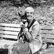 Tatou participe au concours pour gagner de l'argent avec cette photo : bench, black_and_white, casual_clothing, companion, daylight, denim_jacket, dog, glasses, happy, leafy_background, nature, outdoor, park, patterned_skirt, person, pet, seated, short_hair, small_dog, smile