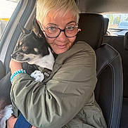 Tatou a rejoint le concours — aidez-le/la à gagner de superbes lots ! woman, dog, person, pet, puppy, black_and_white_dog, car, car_interior, front_seat, portrait, cuddle, hugging, glasses, short_hair, blonde_hair, jacket, bracelet, window, outdoor_background, animal_companion