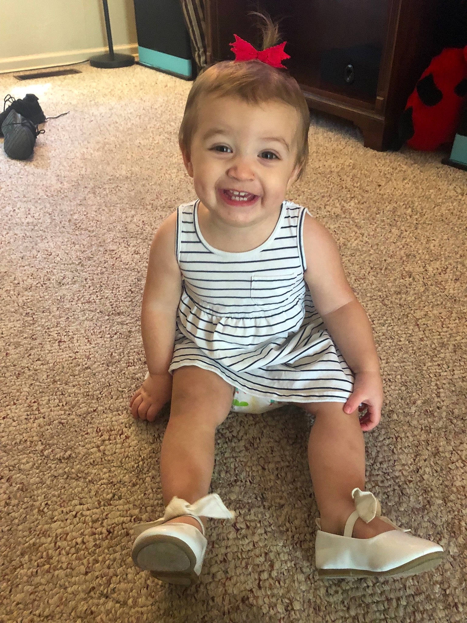 Addison is registered to the contest to win money with this photo: baby, cheek, child, electronic_device, face, facial_expression, footwear, fun, head, joy, leg, person, play, shoe, sitting, skin, smile, standing, t_shirt, toddler