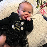 Lila is registered to the contest to win money with this photo: adorable, baby, black_dress, blanket, blue_eyes, cat, celebration, child, cozy, cute, first_new_year, hand_in_mouth, indoor, infant, love_you_pattern, lying_down, pet, smiling, sparkles, tongue_out