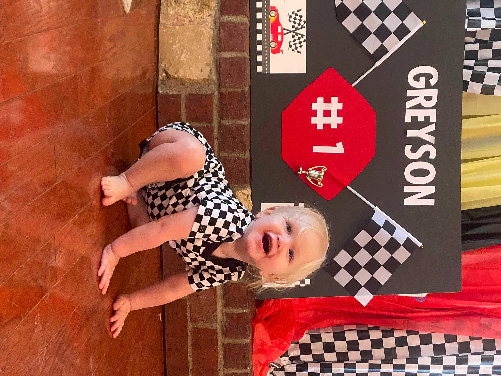 Greyson is registered to the contest to win money with this photo: advertising, design, event, flooring, font, graphic_design, happy, hardwood, human_leg, logo, magenta, pattern, performing_arts, person, red, room, smile, toddler, wood