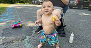 Raeleigh joined the competition — help win amazing prizes! toddler, child, asphalt, outdoor, food, baby_bottle, chalk_drawing, toy, colorful, person, sitting, leg_brace, shorts, bare_chest, smiling, daylight, car, shoe, road, grass