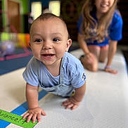 Raeleigh joined the competition — help win amazing prizes! baby, child, crawling, smile, happy, indoor, playroom, mat, blue_clothing, blond_hair, person, young_child, fun, family, focus, background_blur, playful, floor, candid, joy