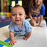 baby, background_blur, blond_hair, blue_clothing, candid, child, crawling, family, floor, focus, fun, happy, indoor, joy, mat, person, playful, playroom, smile, young_child