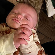 Alexander is registered to the contest to win money with this photo: baby, sleeping, onesie, bear_pattern, hand, face, couch, pillow, cozy, infant, peaceful, rest, closeup, child, indoors, soft_texture, blanket, cute, portrait, relaxation